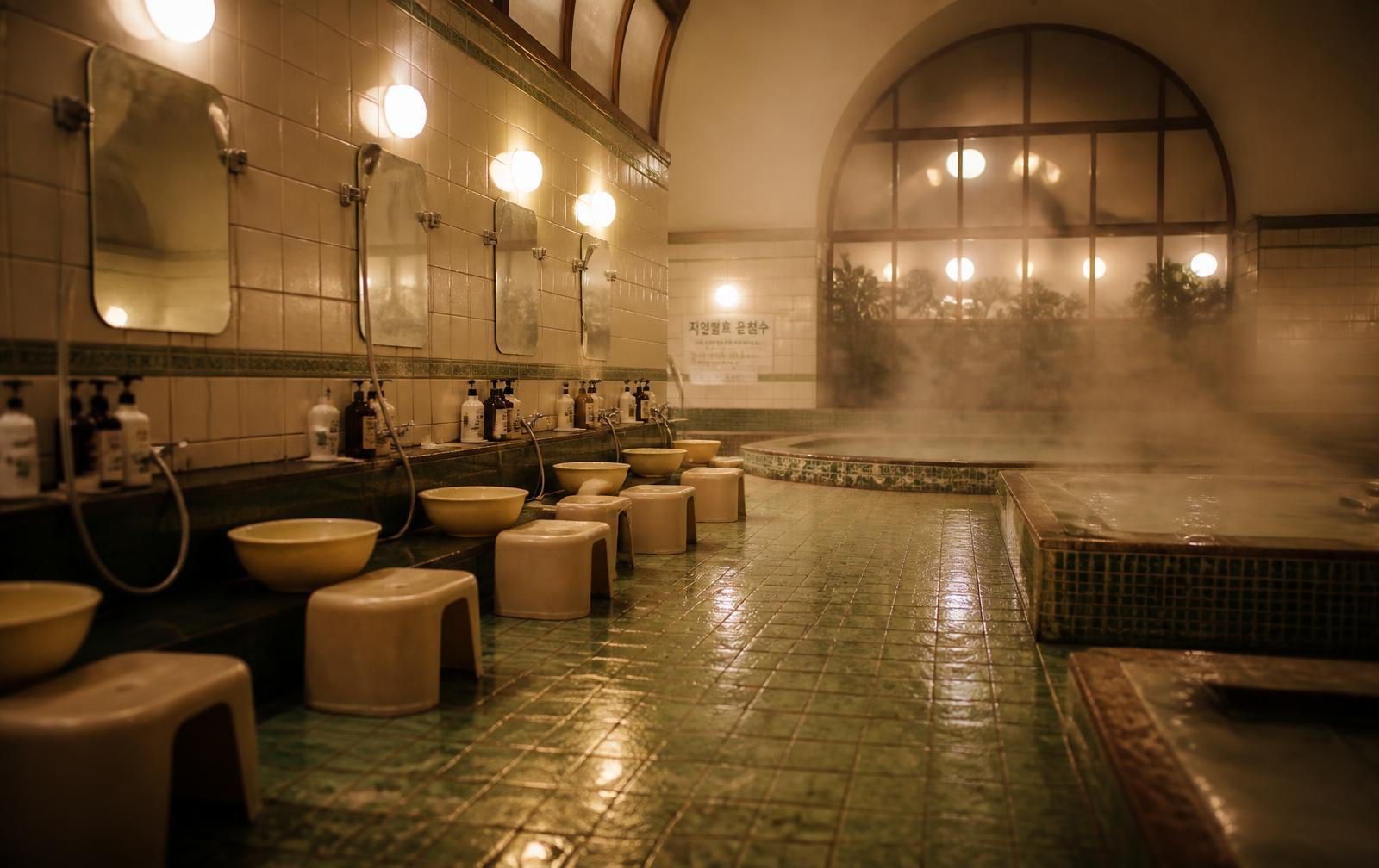 Korean bathhouse interior with steam and bathing stools