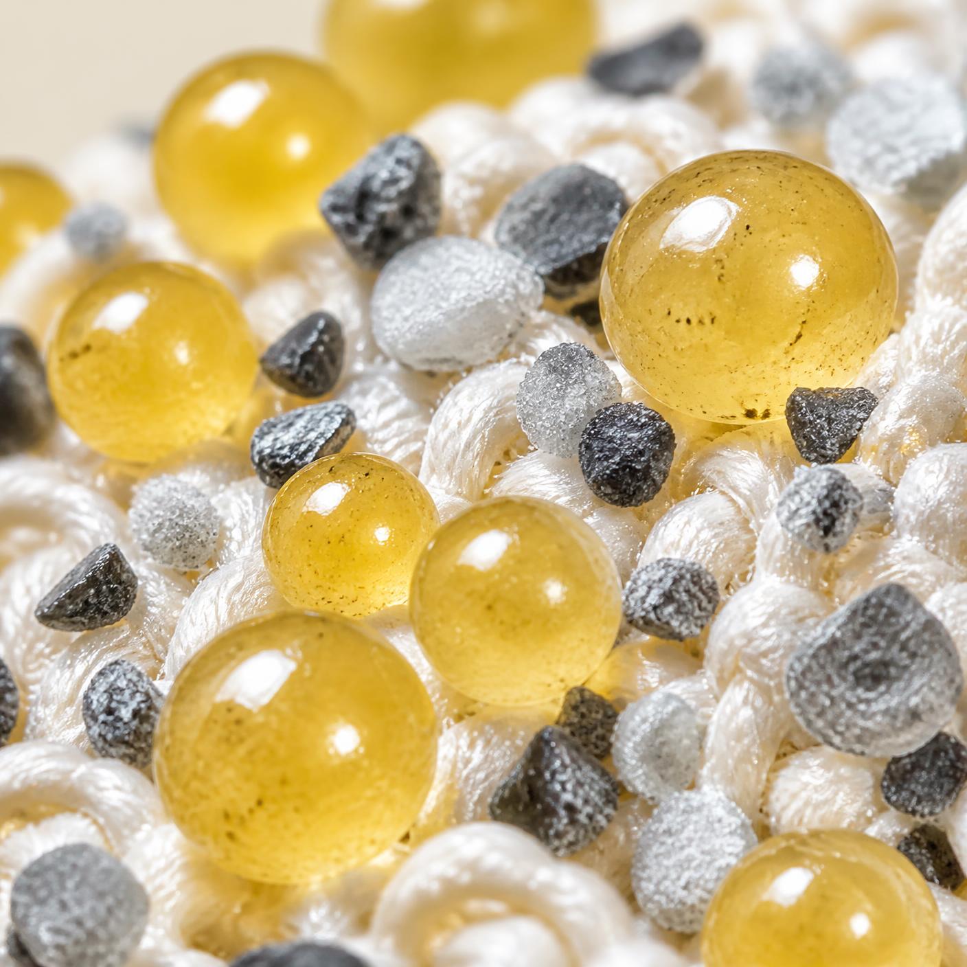Macro view of yellow beauty beads and mineral granules on white fibers